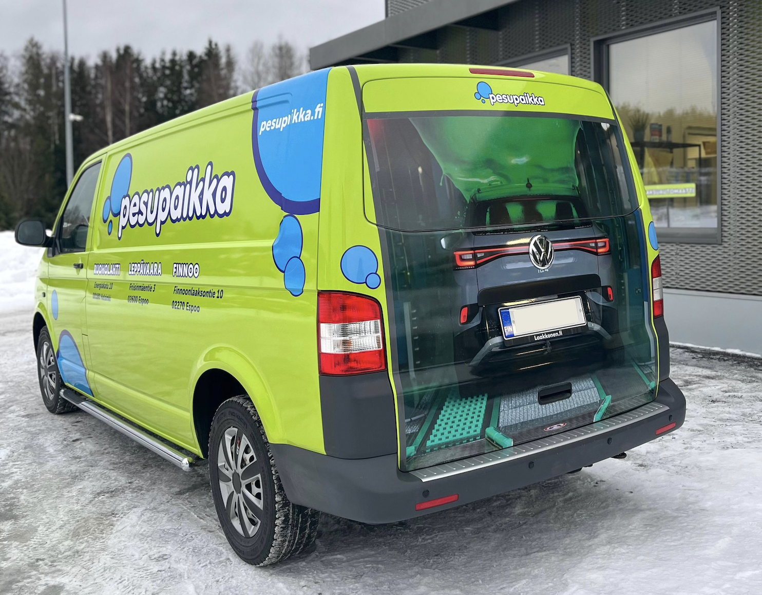 Ajoneuvoteippaus, jossa vihreä väripinta, kuplagrafiikka, logo sekä realistinen kuva auton takaluukussa