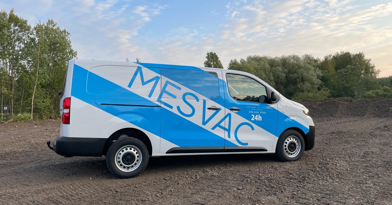 Ajoneuvoteippaus, jossa suuret siniset raidat ja logo auton kyljissä