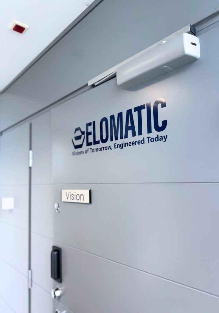 Harmaa ovi, jossa mainosteippauksena Elomatic-logo ja slogan.
