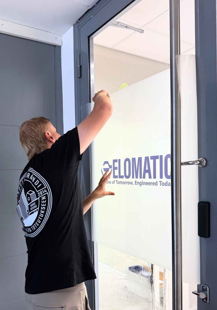 Pääkonttorin oven logolla varustetun maitokalvon asennus.